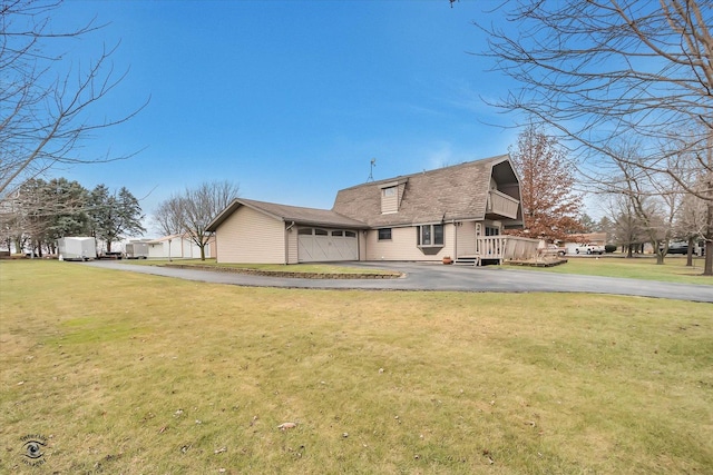 back of house with a garage, a wooden deck, and a lawn