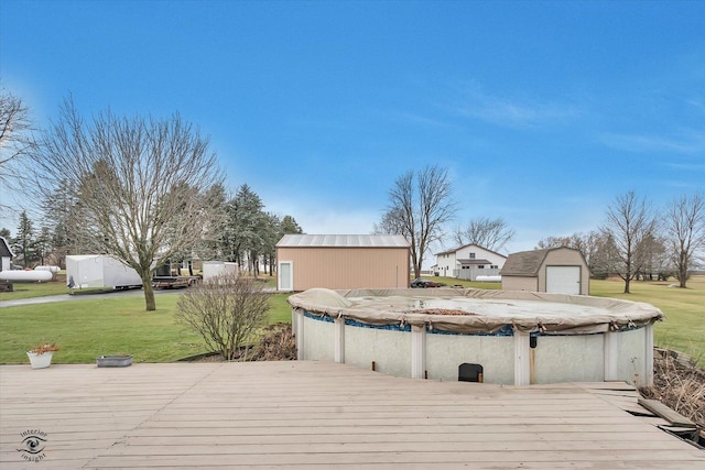 wooden deck with a lawn, an outdoor structure, and a covered pool