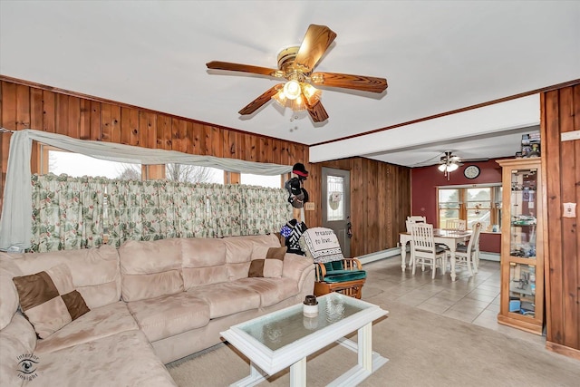 tiled living room with baseboard heating, ceiling fan, and wood walls