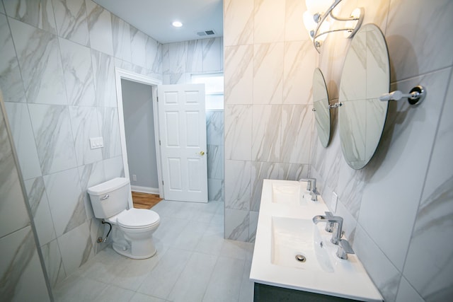 bathroom with tile patterned flooring, vanity, toilet, and tile walls