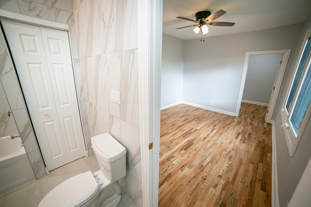 bathroom with hardwood / wood-style flooring, ceiling fan, toilet, and tile walls