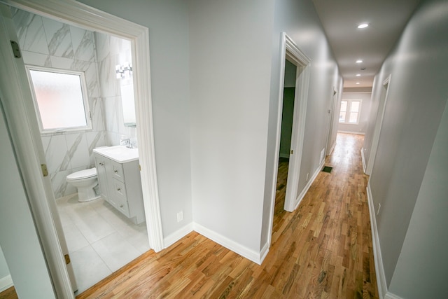 hallway featuring light hardwood / wood-style flooring and tile walls