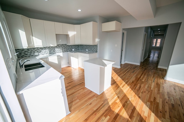 kitchen with tasteful backsplash, white cabinets, light hardwood / wood-style flooring, and a kitchen island