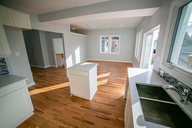 kitchen with light wood-type flooring, tasteful backsplash, and sink