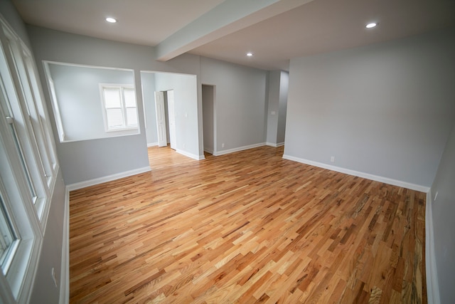 spare room featuring beamed ceiling and light wood-type flooring