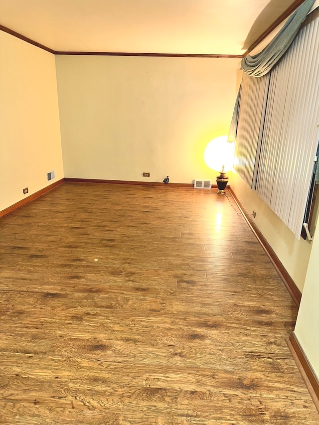 empty room with ornamental molding and hardwood / wood-style flooring