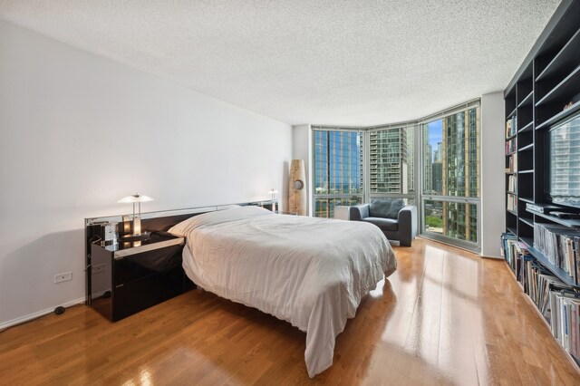 bedroom featuring hardwood / wood-style flooring, a wall of windows, and a textured ceiling