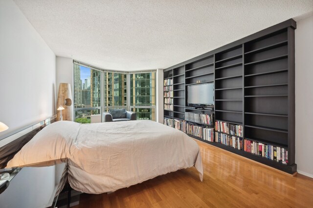 bedroom with floor to ceiling windows, wood-type flooring, and a textured ceiling