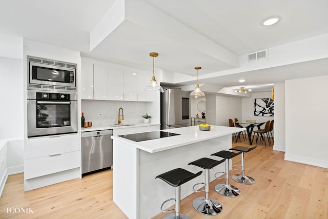 kitchen featuring a breakfast bar, white cabinetry, visible vents, appliances with stainless steel finishes, and a sink
