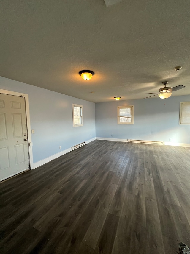 spare room with dark wood-type flooring, a wealth of natural light, and a baseboard heating unit