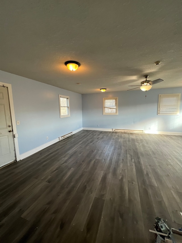 unfurnished room featuring a baseboard radiator, plenty of natural light, and dark hardwood / wood-style flooring