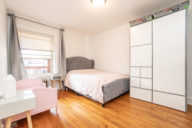 bedroom with radiator and hardwood / wood-style floors