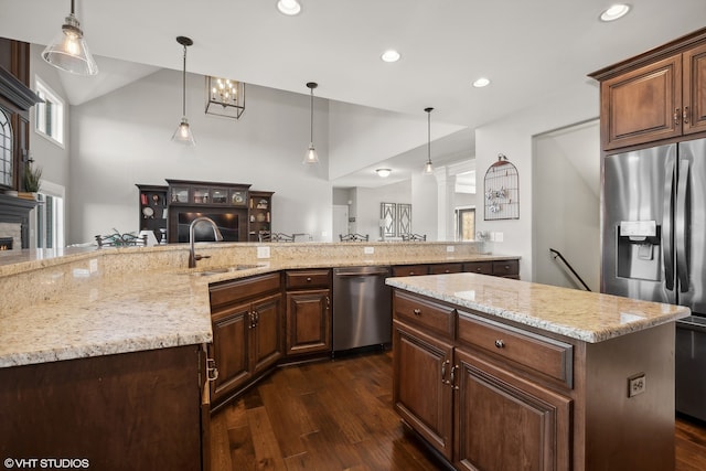 kitchen with appliances with stainless steel finishes, hanging light fixtures, dark hardwood / wood-style floors, and a spacious island