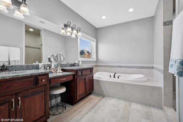 bathroom with vanity, hardwood / wood-style flooring, and plus walk in shower