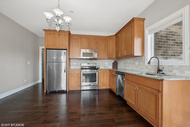 kitchen featuring dark wood-type flooring, sink, light stone countertops, appliances with stainless steel finishes, and decorative light fixtures