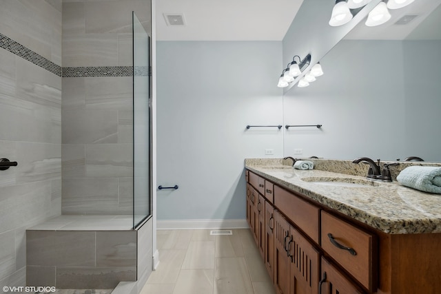 bathroom with tiled shower, tile patterned flooring, and vanity