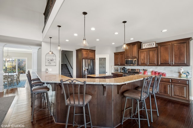 kitchen with dark hardwood / wood-style flooring, hanging light fixtures, a kitchen breakfast bar, and stainless steel appliances