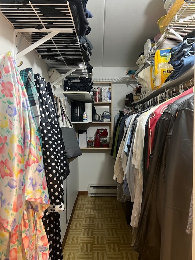 spacious closet with dark parquet floors and a baseboard heating unit