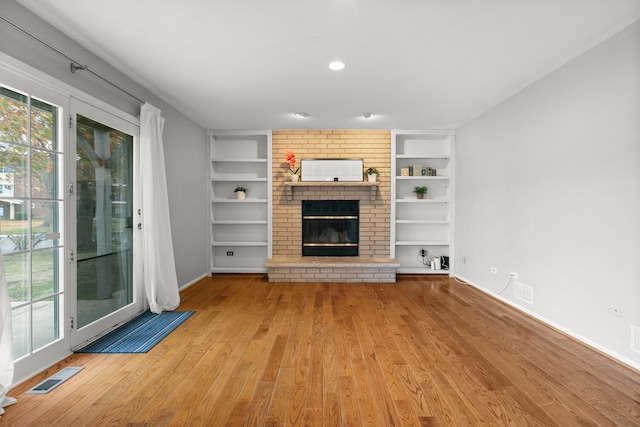 unfurnished living room featuring a brick fireplace and light hardwood / wood-style flooring