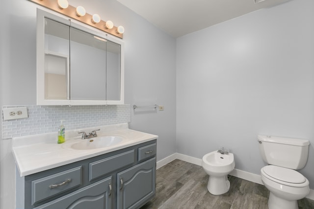 bathroom featuring a bidet, toilet, hardwood / wood-style floors, vanity, and backsplash