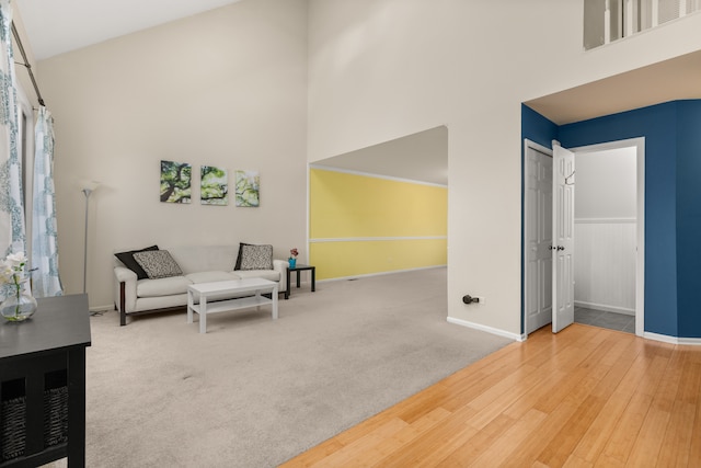 sitting room with a towering ceiling and wood-type flooring