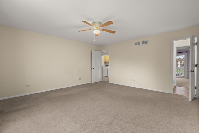 unfurnished room with carpet, ceiling fan, and washer / dryer