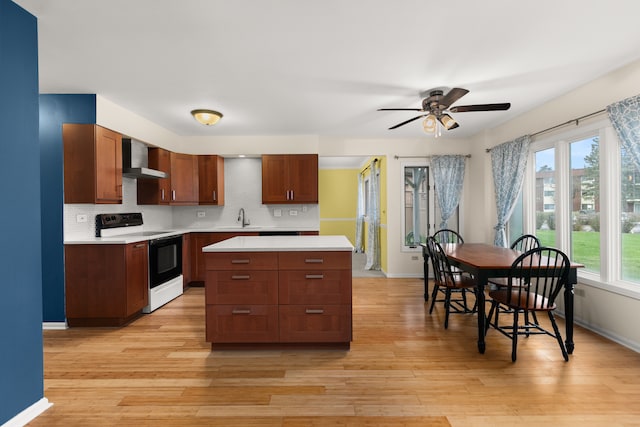 kitchen featuring tasteful backsplash, white range with electric stovetop, wall chimney range hood, sink, and light hardwood / wood-style floors