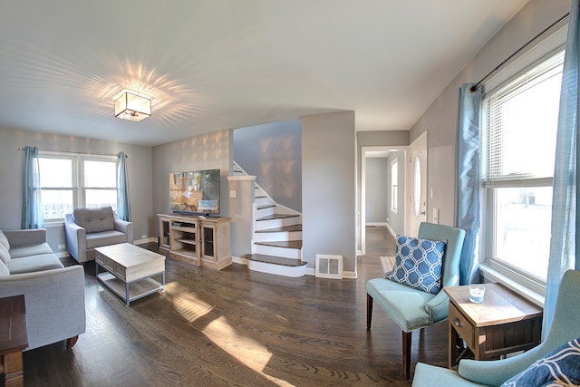 living room featuring dark wood-type flooring and a healthy amount of sunlight