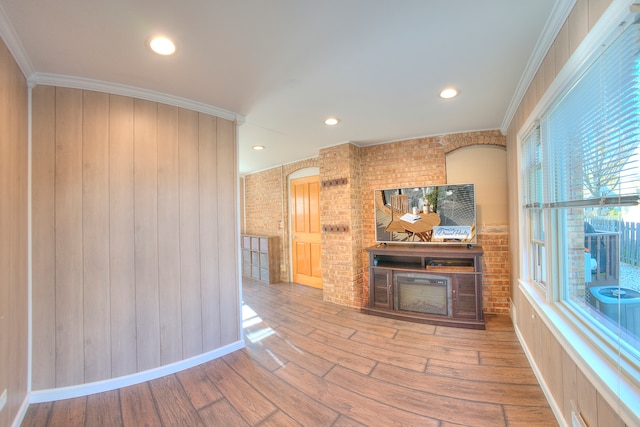 unfurnished living room with ornamental molding, hardwood / wood-style floors, and wood walls