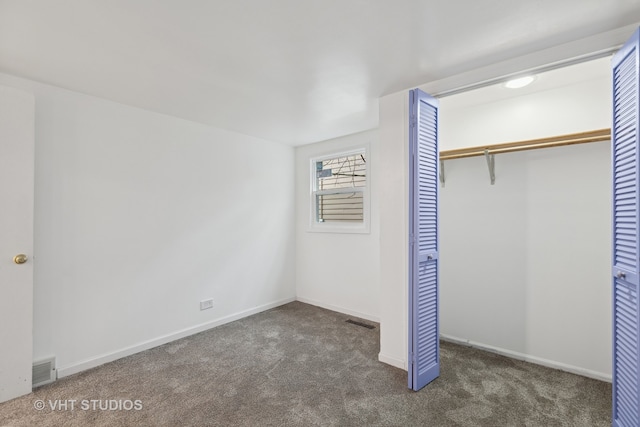 unfurnished bedroom with dark carpet and a closet