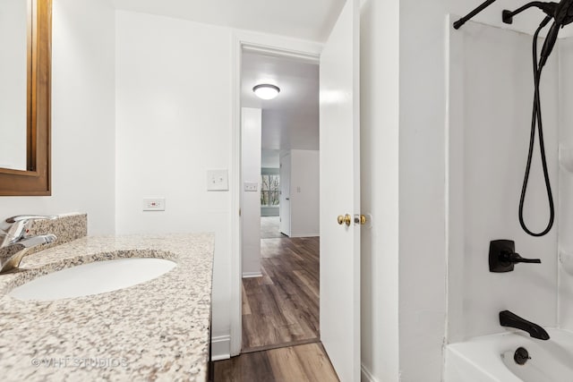 bathroom with washtub / shower combination, hardwood / wood-style floors, and vanity