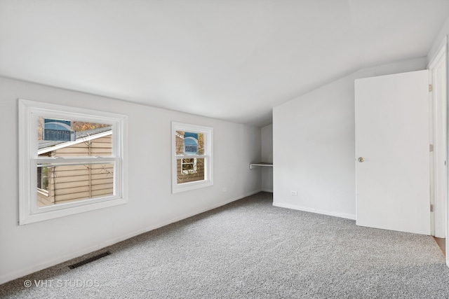 spare room featuring carpet and lofted ceiling