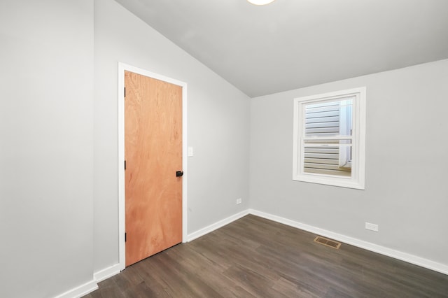 spare room featuring dark hardwood / wood-style floors and vaulted ceiling