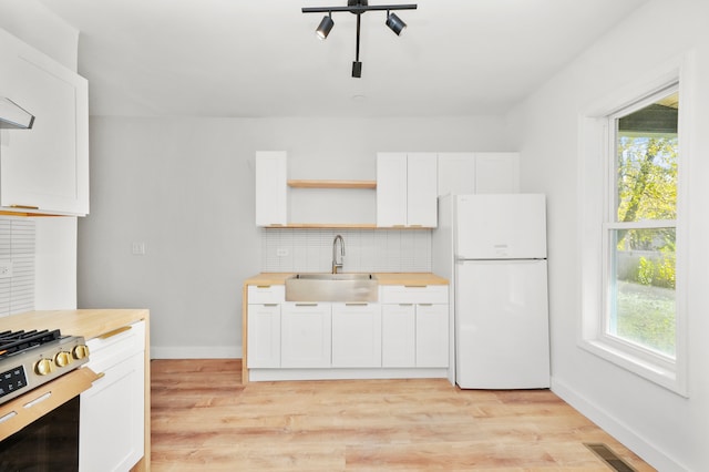 kitchen featuring white cabinetry, white refrigerator, stove, sink, and light hardwood / wood-style floors