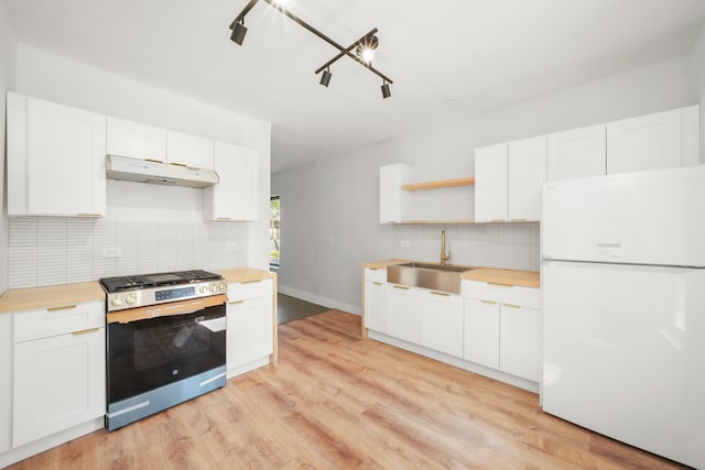 kitchen featuring white cabinets, gas range, sink, and white fridge