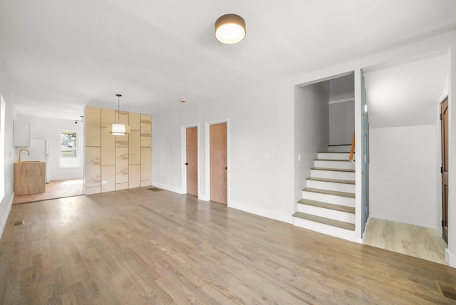 unfurnished living room featuring sink and light hardwood / wood-style flooring