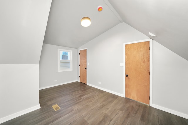 additional living space featuring dark wood-type flooring and vaulted ceiling