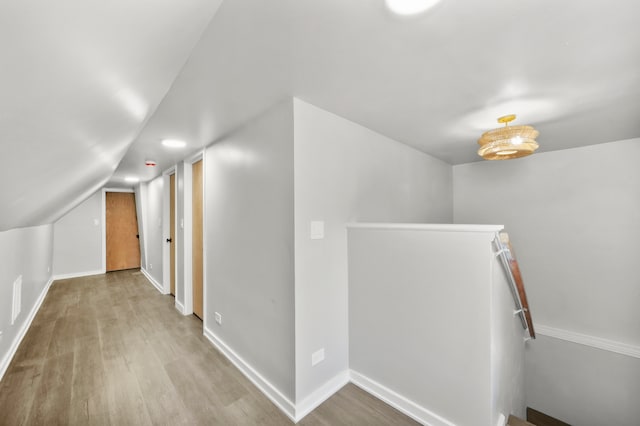 additional living space with light wood-type flooring and vaulted ceiling