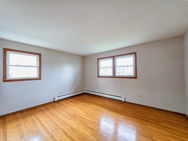 empty room featuring baseboard heating, a healthy amount of sunlight, and light hardwood / wood-style flooring