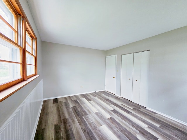 unfurnished bedroom with light hardwood / wood-style flooring, multiple windows, and a closet