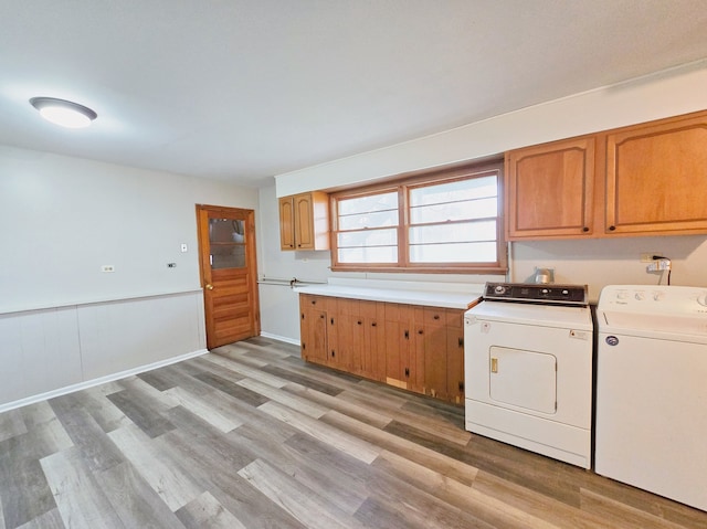 laundry area with light hardwood / wood-style floors, washing machine and dryer, and cabinets