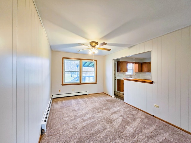 interior space with a baseboard heating unit, wood walls, and ceiling fan