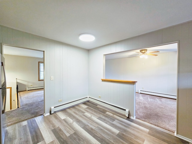 empty room featuring baseboard heating and light hardwood / wood-style flooring