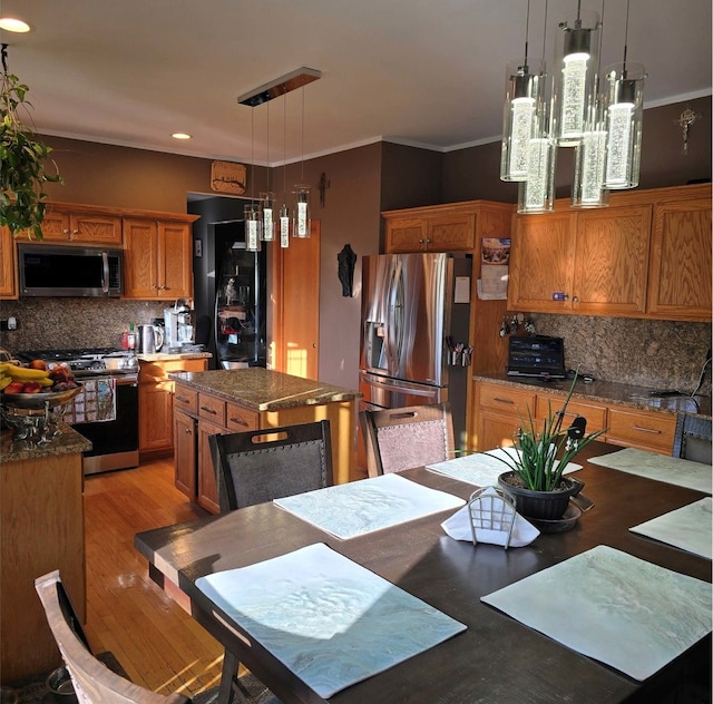 kitchen with stainless steel appliances, a center island, brown cabinets, and decorative light fixtures