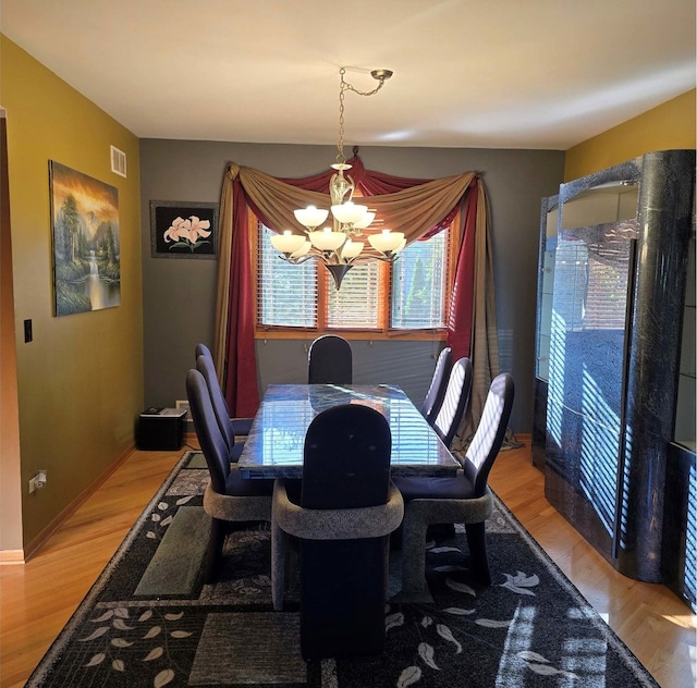 dining area featuring an inviting chandelier, baseboards, visible vents, and wood finished floors