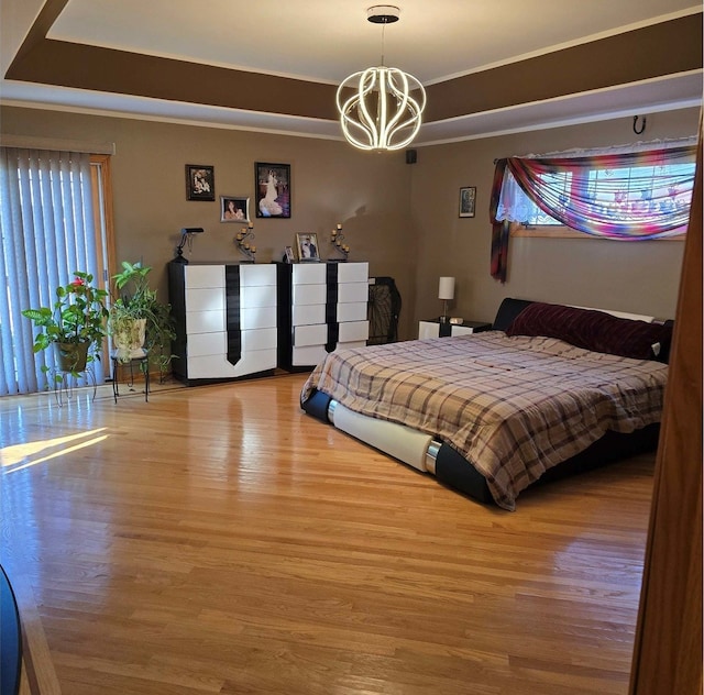 bedroom with wood finished floors, a raised ceiling, and an inviting chandelier