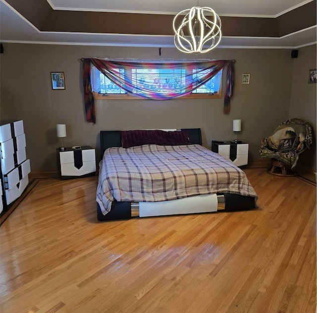 bedroom featuring wood finished floors, a raised ceiling, and crown molding