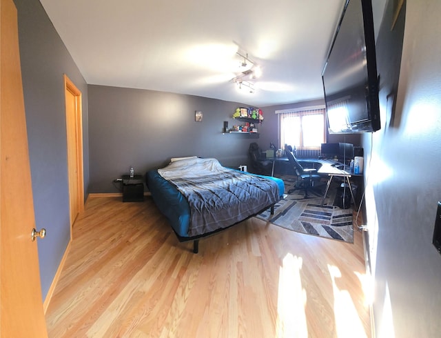 bedroom with light wood-style floors, baseboards, and track lighting