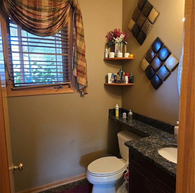 half bathroom with toilet, vanity, and baseboards