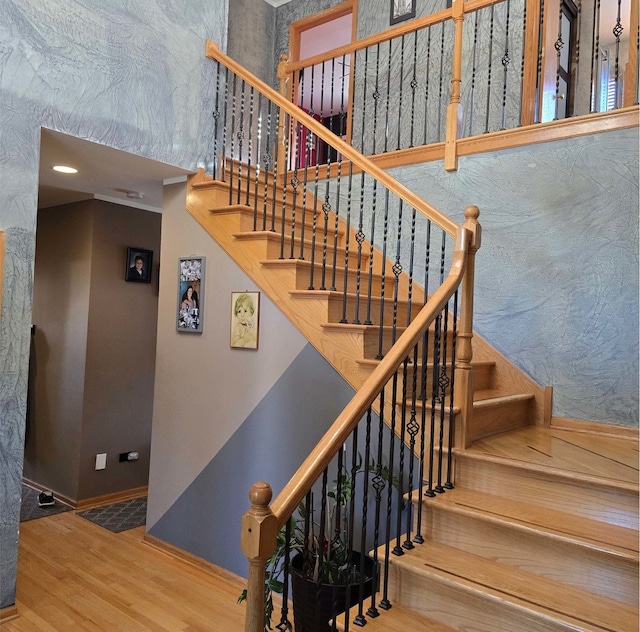 stairs with a towering ceiling, baseboards, and wood finished floors